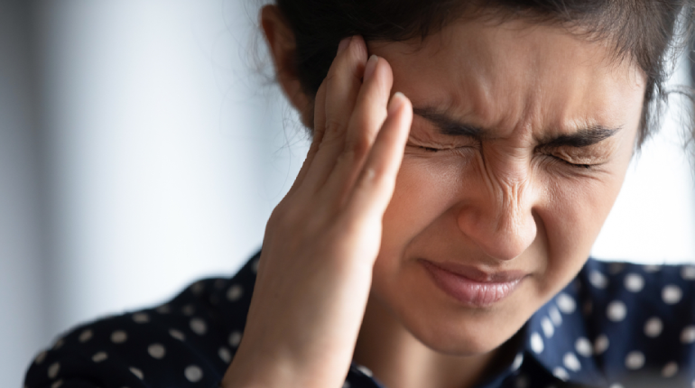 Person with a headache from a cold, holding their forehead